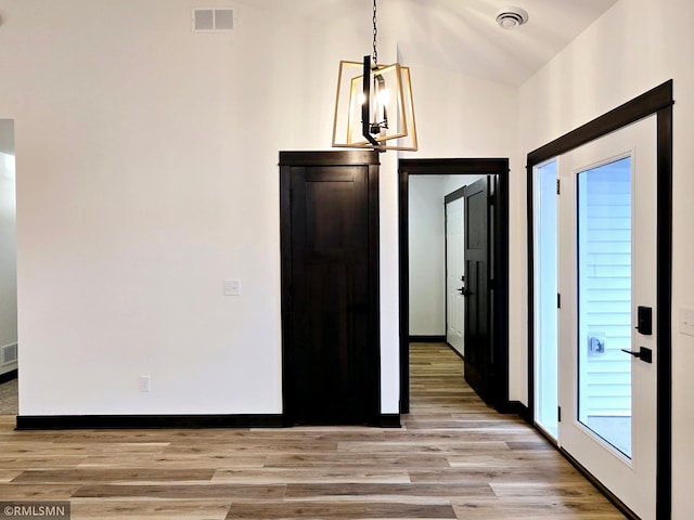 interior space featuring a chandelier, visible vents, light wood finished floors, and baseboards