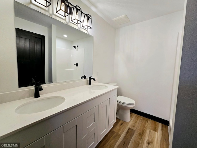 bathroom featuring wood finished floors, a sink, a shower, and toilet