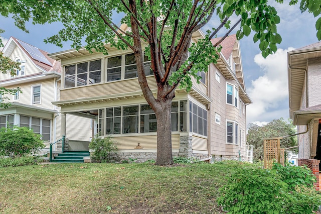 back of property featuring a lawn and a sunroom