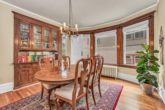 dining space with light wood-type flooring, baseboards, crown molding, and a chandelier