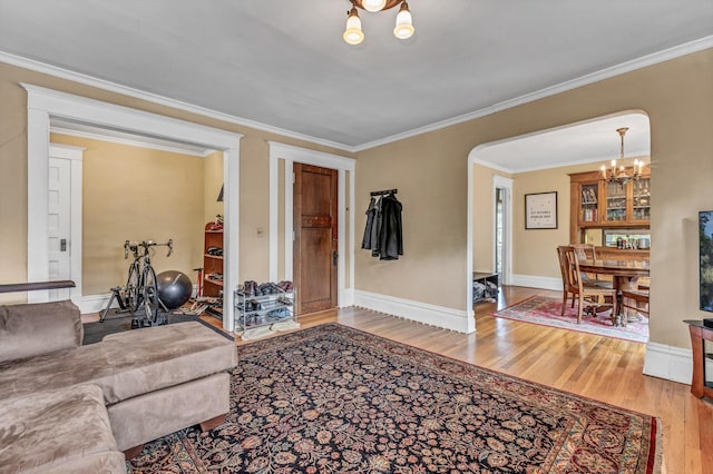 living area featuring arched walkways, an inviting chandelier, ornamental molding, and wood finished floors