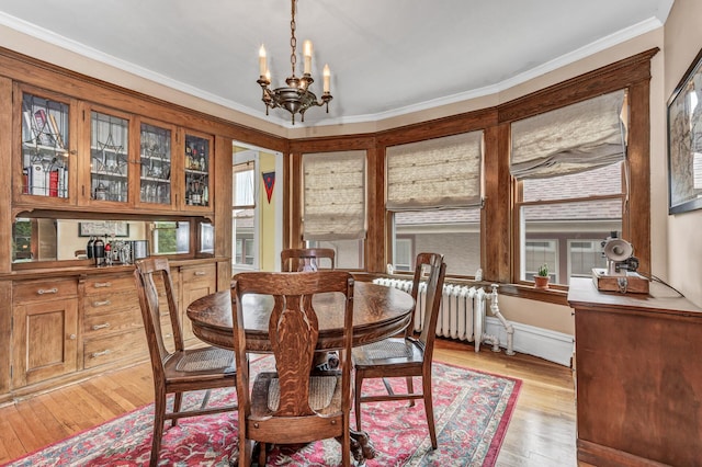 dining space with light wood-style floors, an inviting chandelier, plenty of natural light, crown molding, and radiator heating unit