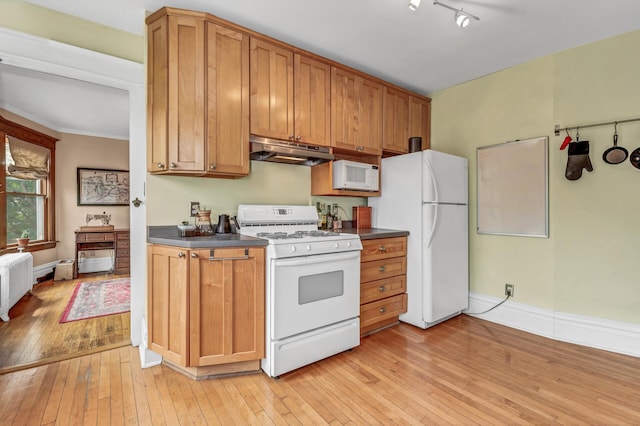 kitchen featuring dark countertops, light wood-type flooring, radiator heating unit, under cabinet range hood, and white appliances