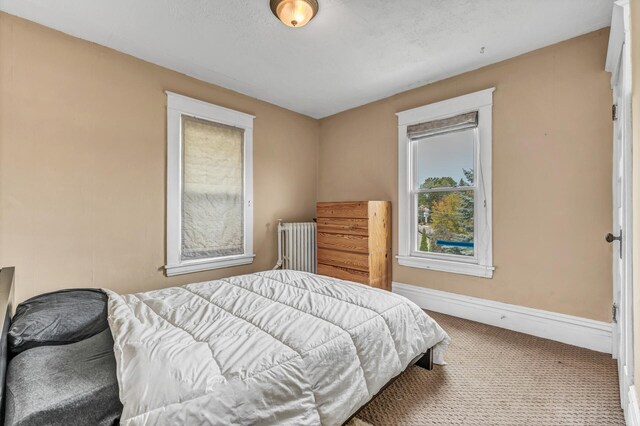 bedroom with baseboards, carpet, and radiator