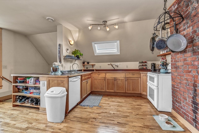 kitchen with light wood-type flooring, a sink, a peninsula, and white appliances