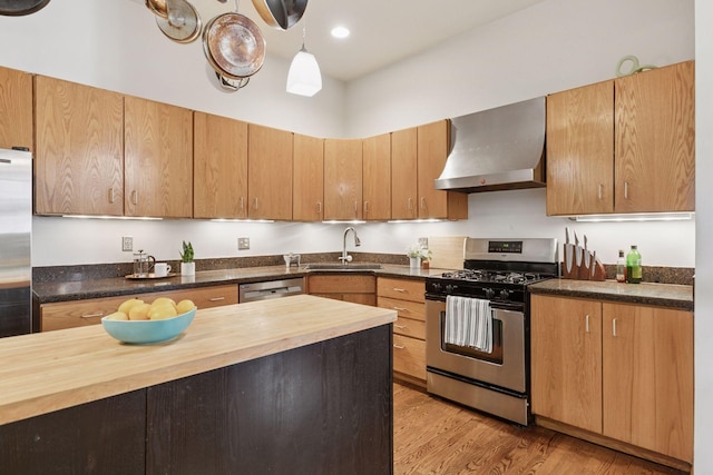 231 Arundel St Unit 1, Saint Paul, MN 55102 - kitchen featuring wall chimney range hood, stainless steel appliances, butcher block countertops, light wood-type flooring, and hanging light fixtures