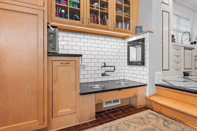 818 Summit Ave, Saint Paul, MN 55105 - kitchen featuring decorative backsplash, glass insert cabinets, and dark countertops