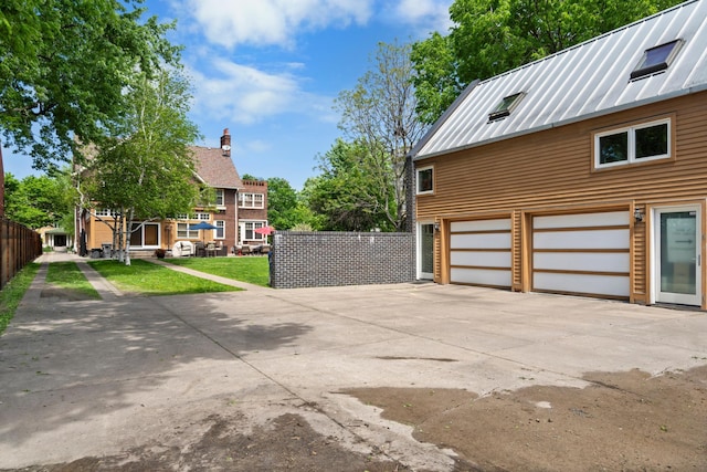 818 Summit Ave, Saint Paul, MN 55105 - view of side of property featuring driveway, an attached garage, a standing seam roof, and metal roof