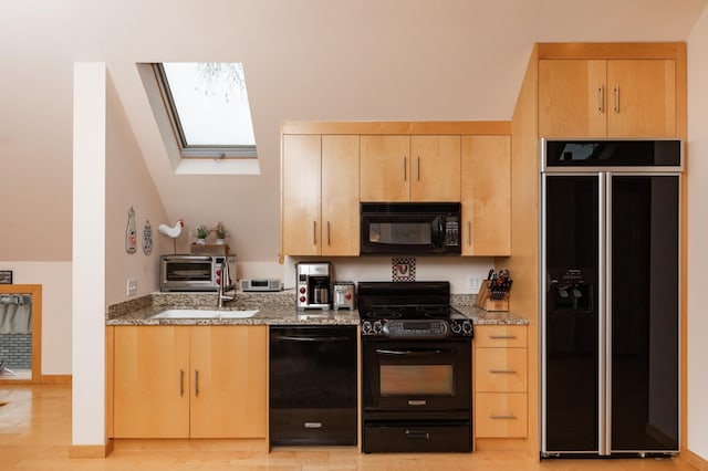 818 Summit Ave, Saint Paul, MN 55105 - kitchen featuring black appliances, a skylight, light brown cabinets, light stone countertops, and vaulted ceiling