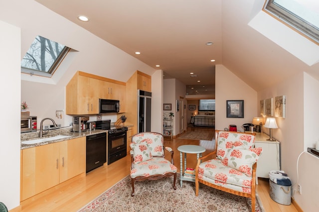818 Summit Ave, Saint Paul, MN 55105 - kitchen featuring a skylight, black appliances, a sink, light brown cabinetry, and light wood-style floors