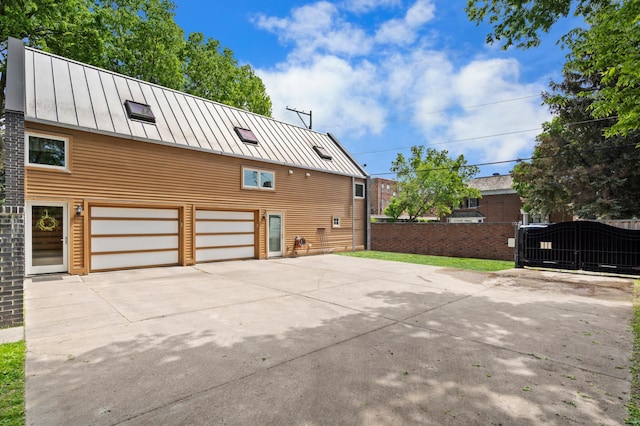 818 Summit Ave, Saint Paul, MN 55105 - view of side of home featuring a standing seam roof, an attached garage, concrete driveway, fence, and metal roof