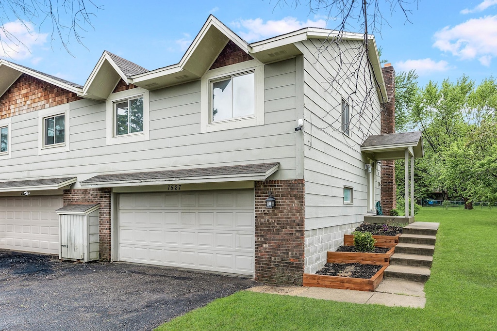 7527 102nd St, Bloomington, MN 55438 - view of side of home featuring an attached garage, a yard, and brick siding