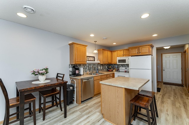 kitchen featuring light wood-style flooring, white appliances, light countertops, and a sink