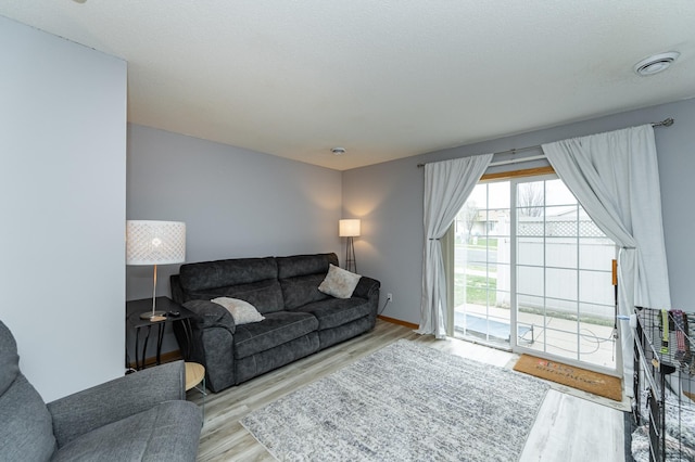 living room with baseboards, visible vents, and wood finished floors