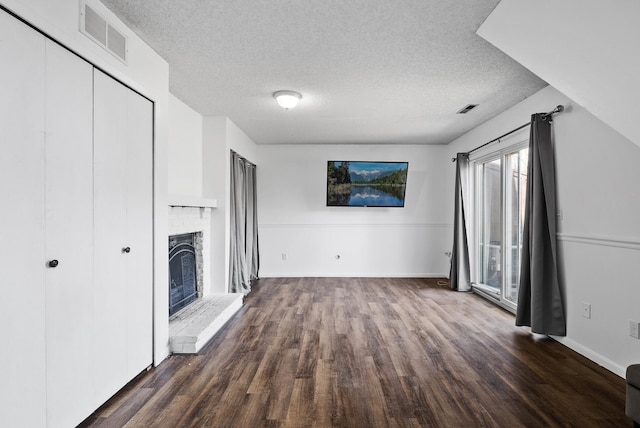 unfurnished living room featuring dark wood-style flooring, a textured ceiling, baseboards, and a fireplace