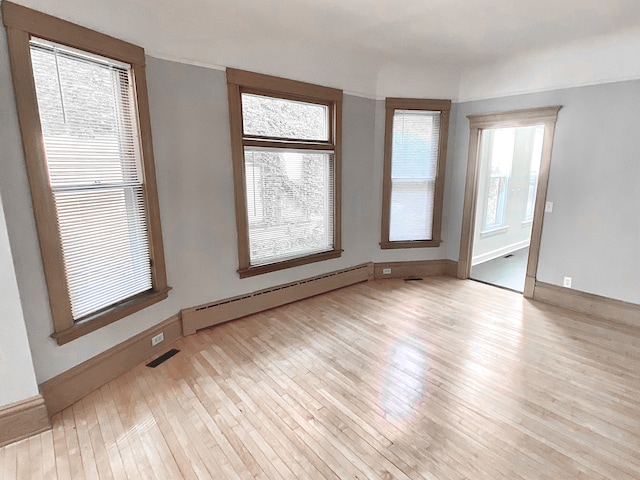 1605 Dupont Ave N, Minneapolis, MN 55411 - spare room with baseboards, baseboard heating, visible vents, and hardwood / wood-style flooring