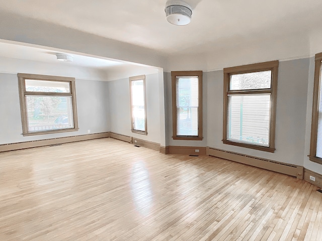 1605 Dupont Ave N, Minneapolis, MN 55411 - unfurnished room with a baseboard heating unit, a healthy amount of sunlight, baseboard heating, and light wood finished floors