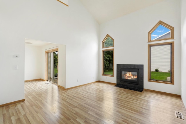 8722 Norway St NW, Coon Rapids, MN 55433 - unfurnished living room featuring high vaulted ceiling, light wood finished floors, a tiled fireplace, and baseboards