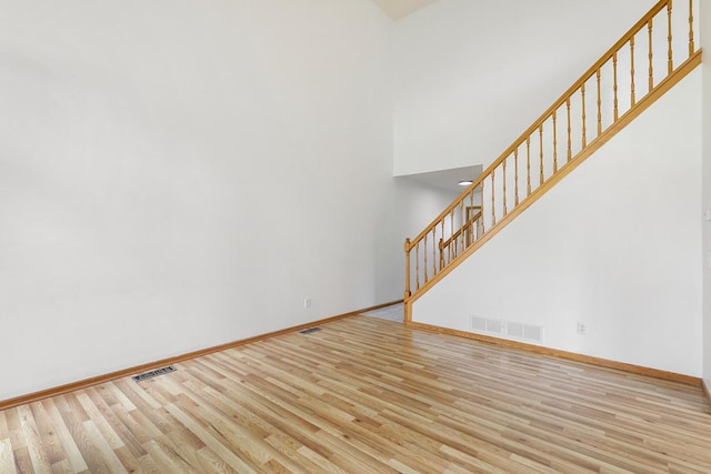 8722 Norway St NW, Coon Rapids, MN 55433 - unfurnished living room featuring stairway, wood finished floors, baseboards, and a high ceiling