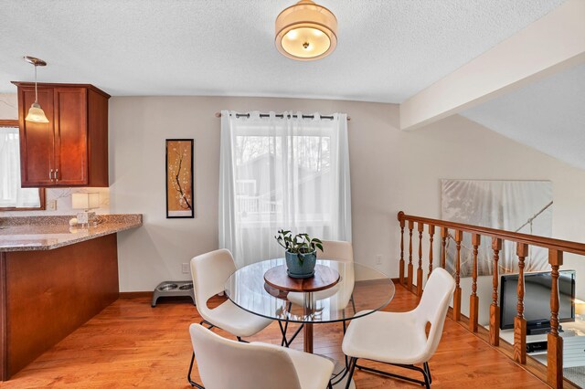 dining space with a textured ceiling and light wood-style flooring