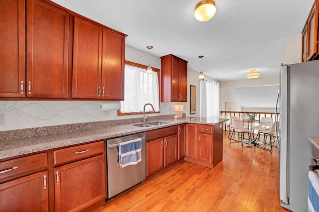 kitchen featuring tasteful backsplash, light wood-style flooring, stainless steel appliances, a sink, and a peninsula