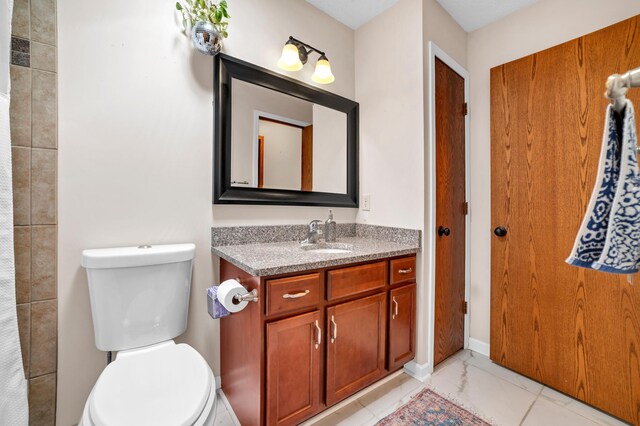 bathroom with toilet, marble finish floor, and vanity