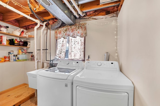 washroom featuring a sink, washing machine and clothes dryer, laundry area, visible vents, and wood finished floors