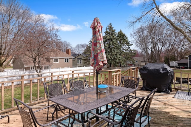 wooden terrace featuring outdoor dining space, area for grilling, a fenced backyard, and a yard