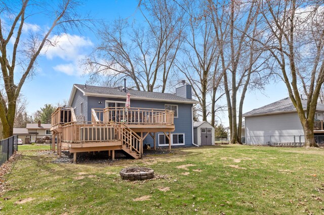 back of property with a deck, a chimney, a fire pit, fence, and a storage unit