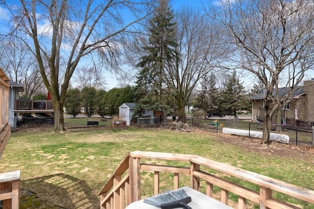 view of yard with an outbuilding, a storage shed, a deck, and fence