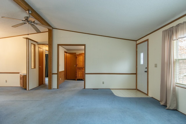 unfurnished room with light colored carpet, ornamental molding, vaulted ceiling, and a ceiling fan