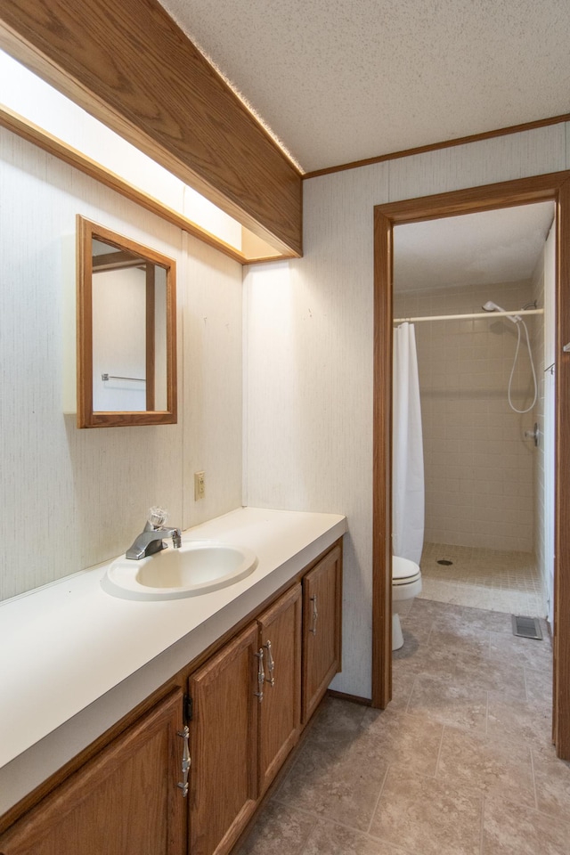 full bathroom with a shower stall, toilet, vanity, ornamental molding, and a textured ceiling