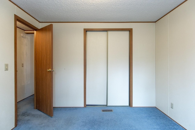 unfurnished bedroom with a textured ceiling, carpet floors, visible vents, and crown molding
