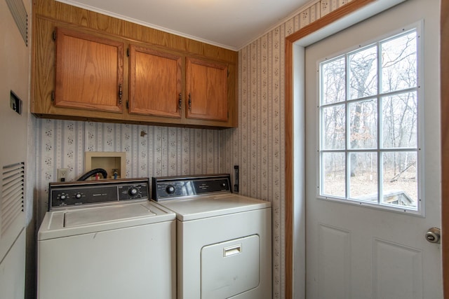 laundry room with cabinet space, wallpapered walls, washer and dryer, and ornamental molding