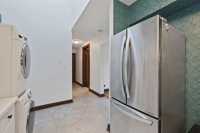 1707 Stevens Ave Unit 306, Minneapolis, MN 55403 - kitchen featuring wallpapered walls, stacked washing maching and dryer, white cabinets, baseboards, and freestanding refrigerator