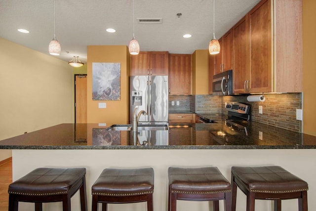 240 Spring St Unit 331, Saint Paul, MN 55102 - kitchen featuring brown cabinets, decorative backsplash, a peninsula, and stainless steel appliances