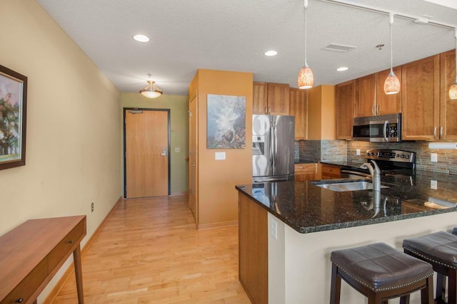240 Spring St Unit 331, Saint Paul, MN 55102 - kitchen featuring a peninsula, brown cabinets, backsplash, and appliances with stainless steel finishes