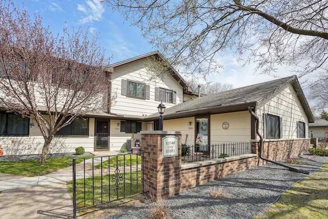 view of front of house with a shingled roof and a fenced front yard