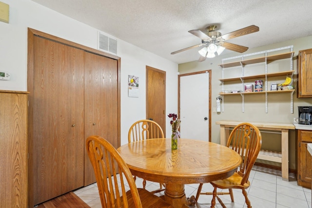 dining space featuring a ceiling fan, a textured ceiling, visible vents, and light tile patterned floors