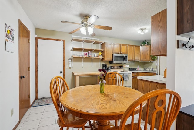 kitchen featuring white range with electric cooktop, light countertops, a textured ceiling, stainless steel microwave, and a ceiling fan
