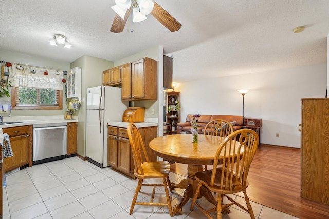kitchen featuring brown cabinets, ceiling fan, light countertops, a textured ceiling, and stainless steel dishwasher