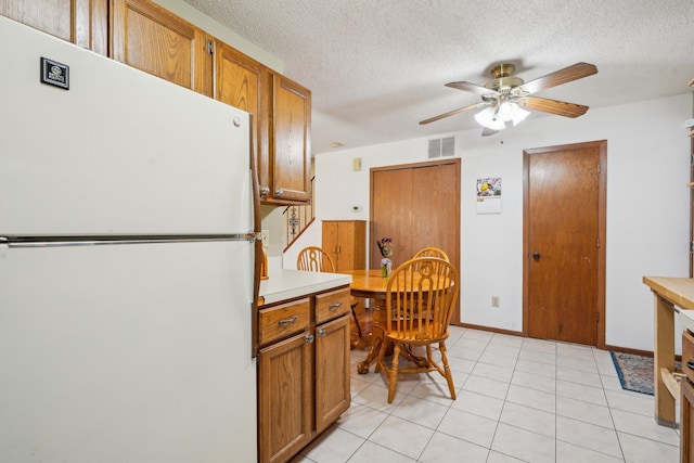kitchen featuring ceiling fan, visible vents, brown cabinets, light countertops, and freestanding refrigerator
