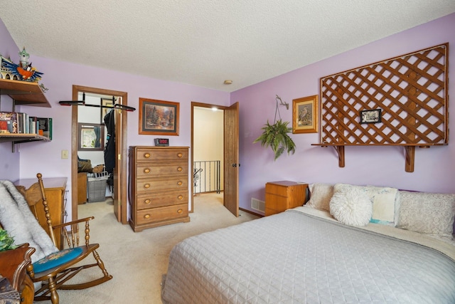 bedroom featuring light colored carpet, a textured ceiling, and visible vents