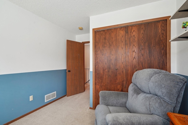 living area featuring baseboards, carpet flooring, a textured ceiling, and visible vents