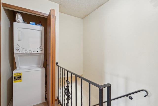 laundry area with a textured ceiling, laundry area, and stacked washing maching and dryer