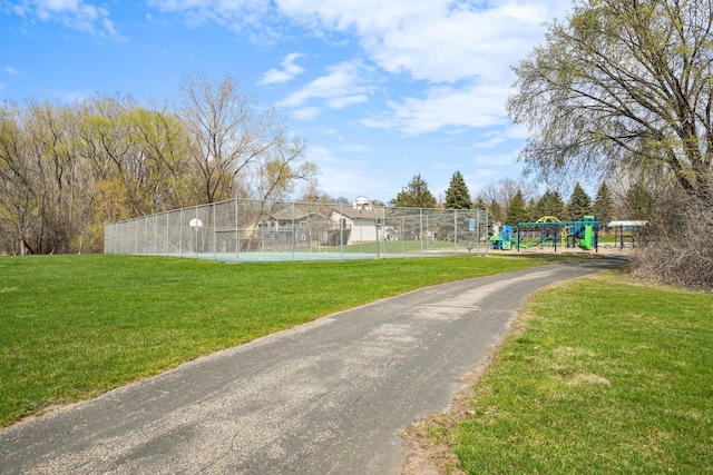 view of community featuring a yard, fence, and playground community