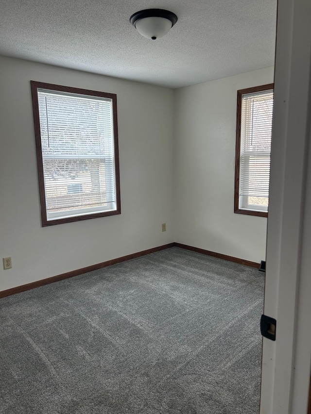 carpeted spare room featuring baseboards and a textured ceiling