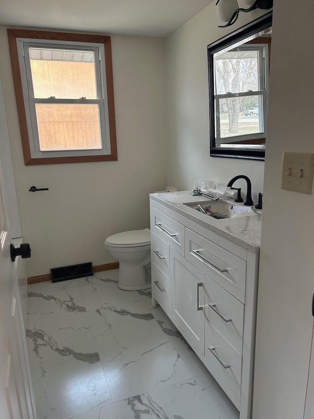 bathroom with visible vents, toilet, vanity, and a wealth of natural light