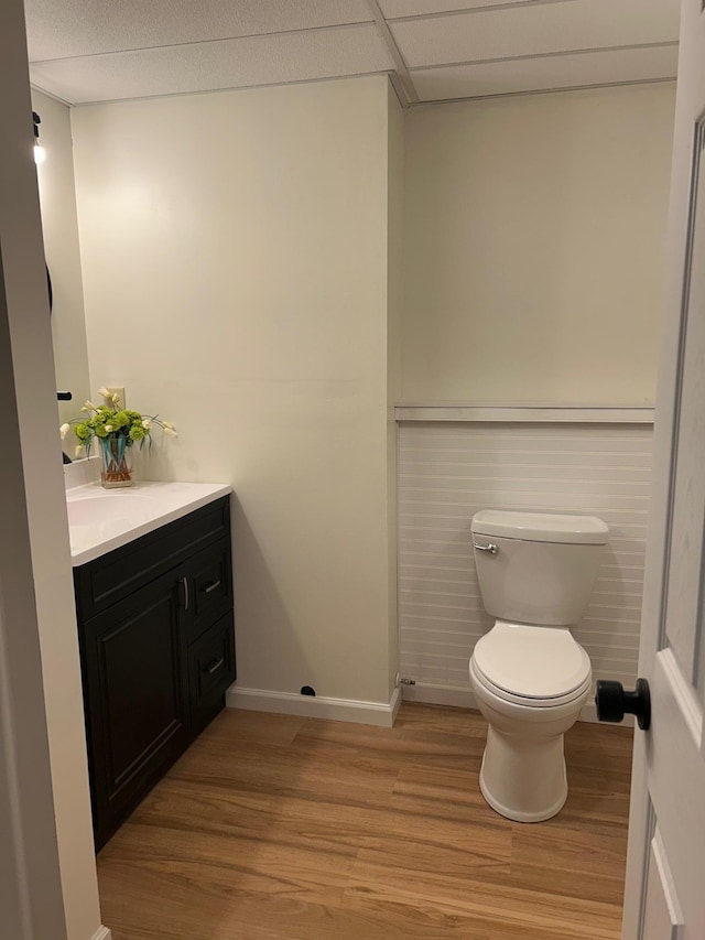 bathroom with toilet, vanity, wood finished floors, and baseboards