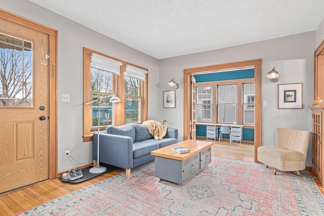 living room with wood finished floors, a textured ceiling, and baseboards